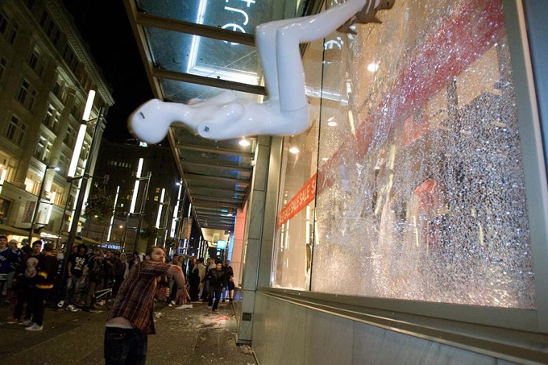 A man throws a mannequin into a window on granville street during the Stanley Cup Riots