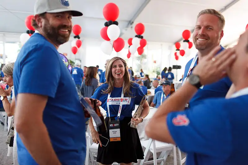 Event photography of CARSTAR conference attendees laughing together in branded shirts at the Victoria Conference Centre