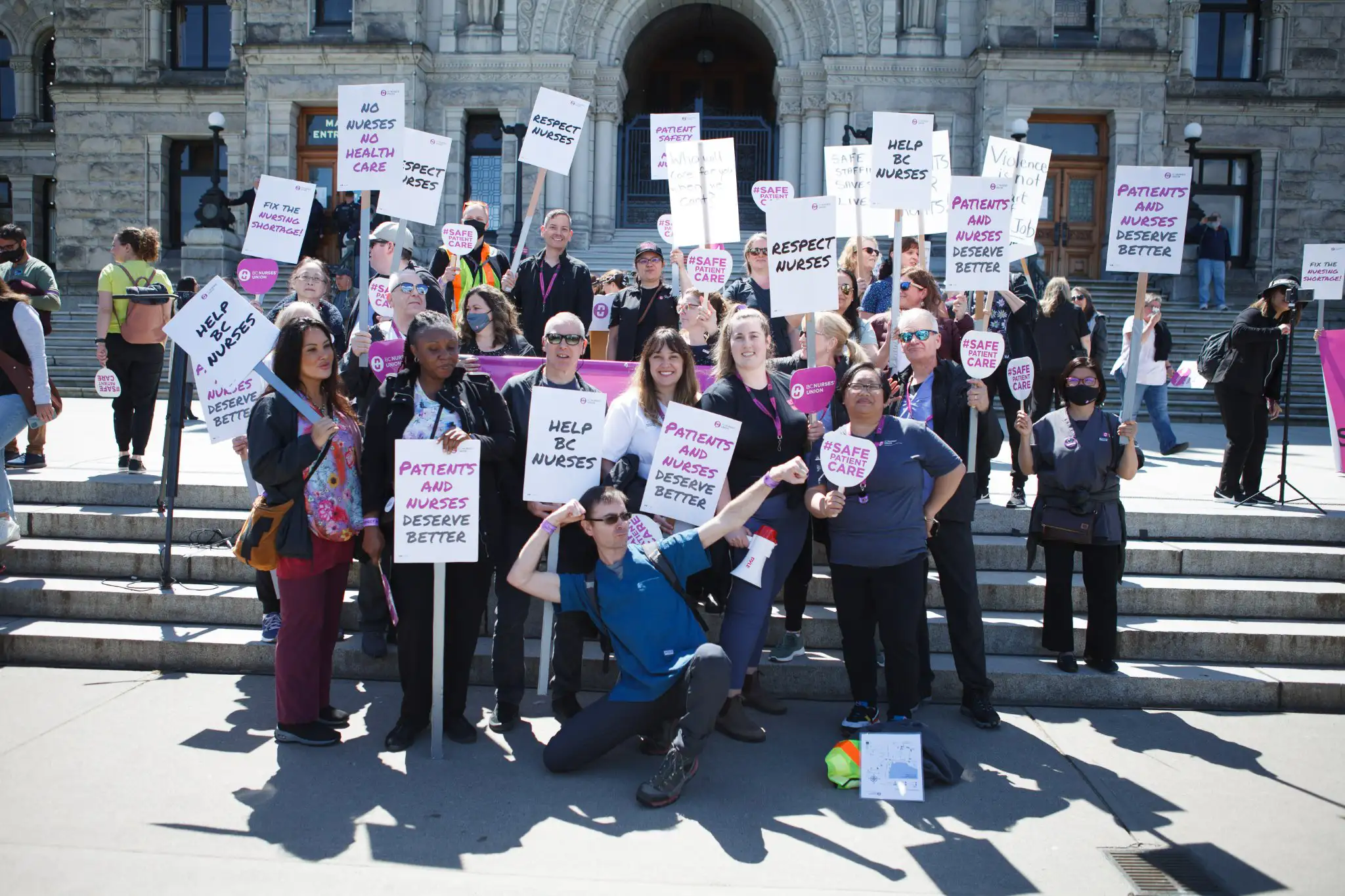 BC Nurses union members pose in front of the BC Legislature during a rally
