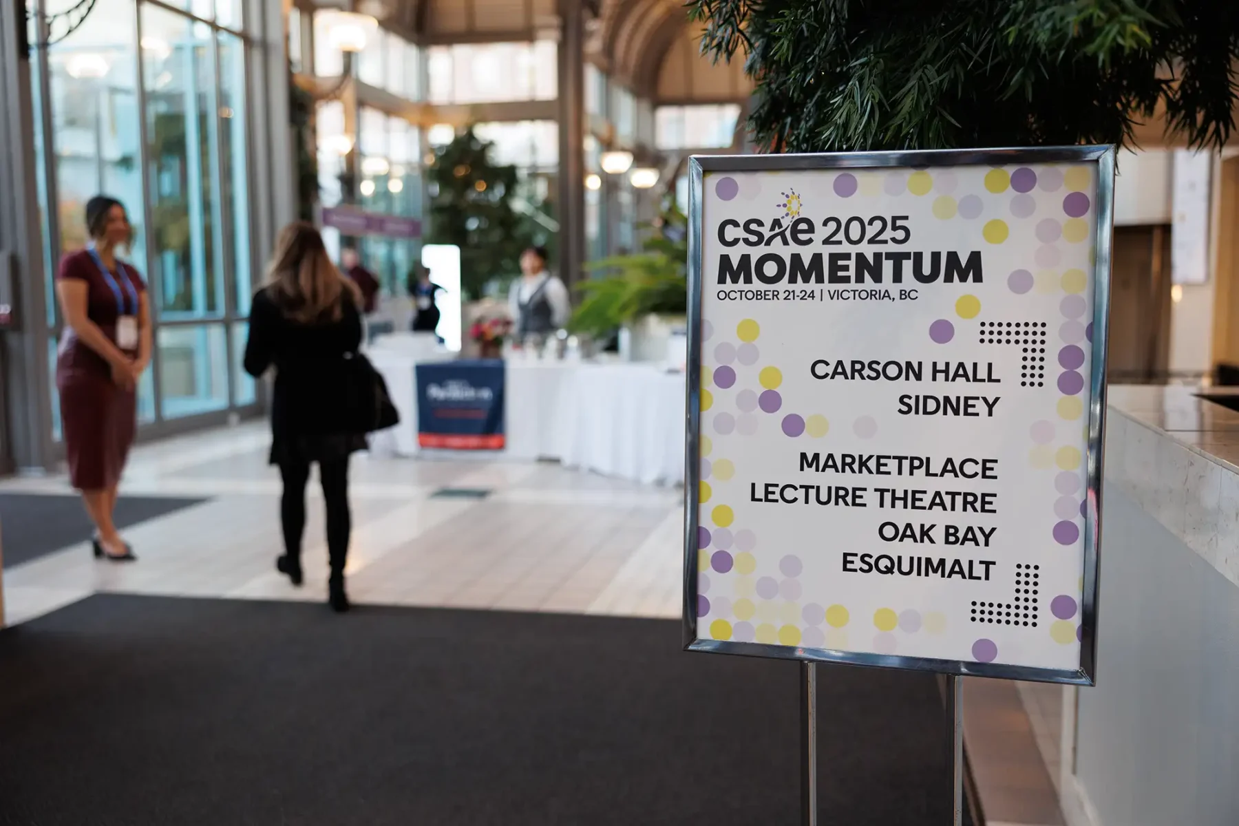 A branding sign with people walking in the background at the Victoria Conference Centre
