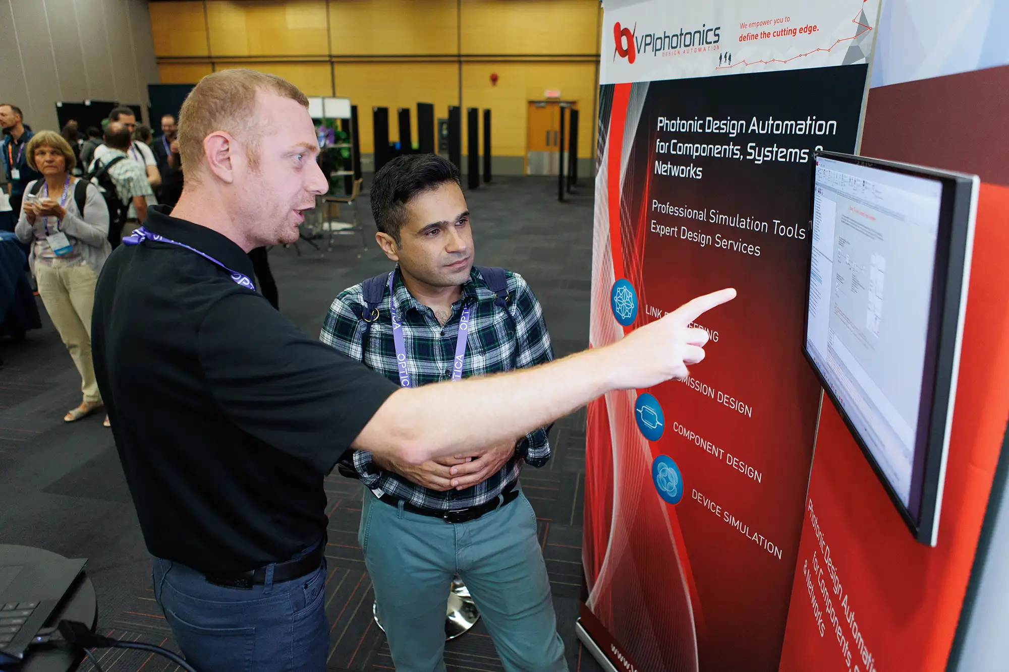 a trade show vendor points to information while speaking with a conference attendee