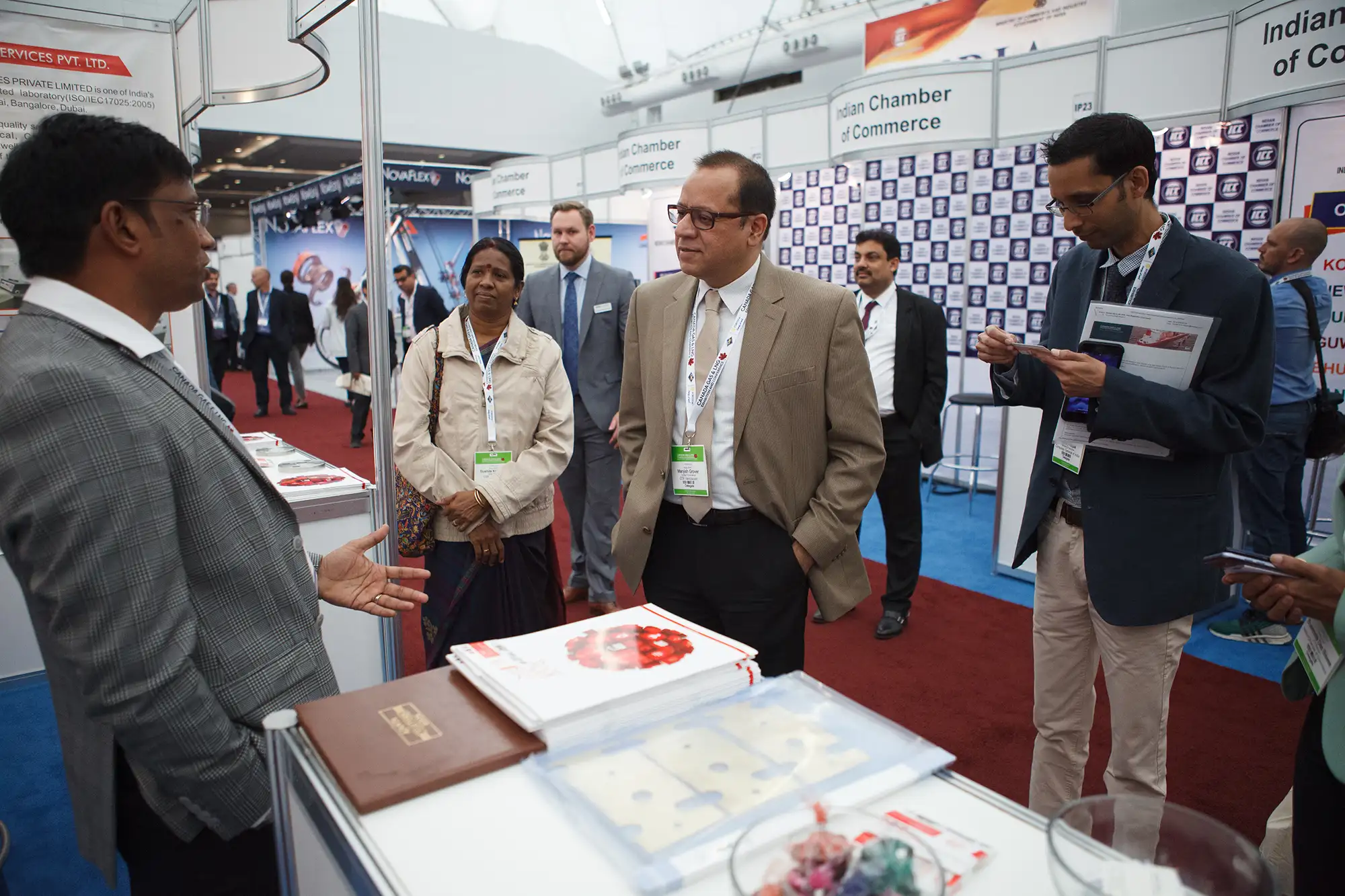 a group of conference attendees speak with an exhibitor at their booth during the Canada LNG conference in Vancouver